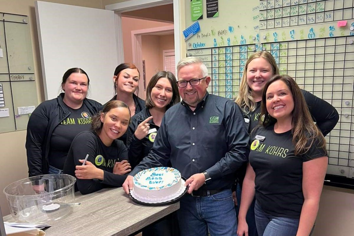 Expert, top rated Kohrs Orthodontics team surrounding Dr. Kohrs with "Best Boss Ever" cake