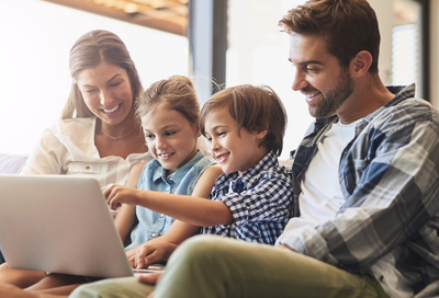 Family sitting on a couch, interacting with a laptop computer, representing Kohrs Orthodontics' new website