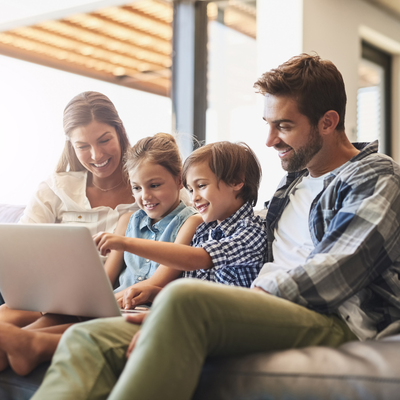 Family sitting on a couch, interacting with a laptop computer, representing Kohrs Orthodontics' new website